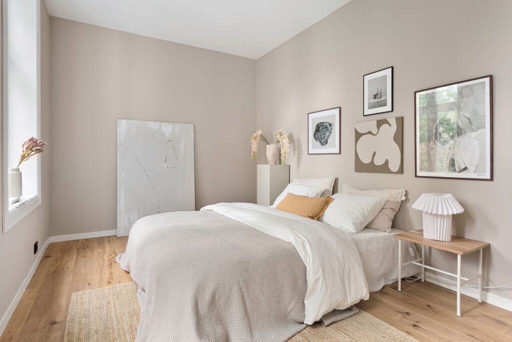 A serene minimalist bedroom with neutral tones, modern art, and soft bedding.