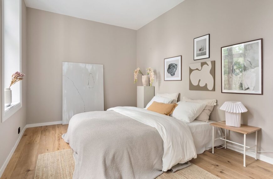 A serene minimalist bedroom with neutral tones, modern art, and soft bedding.