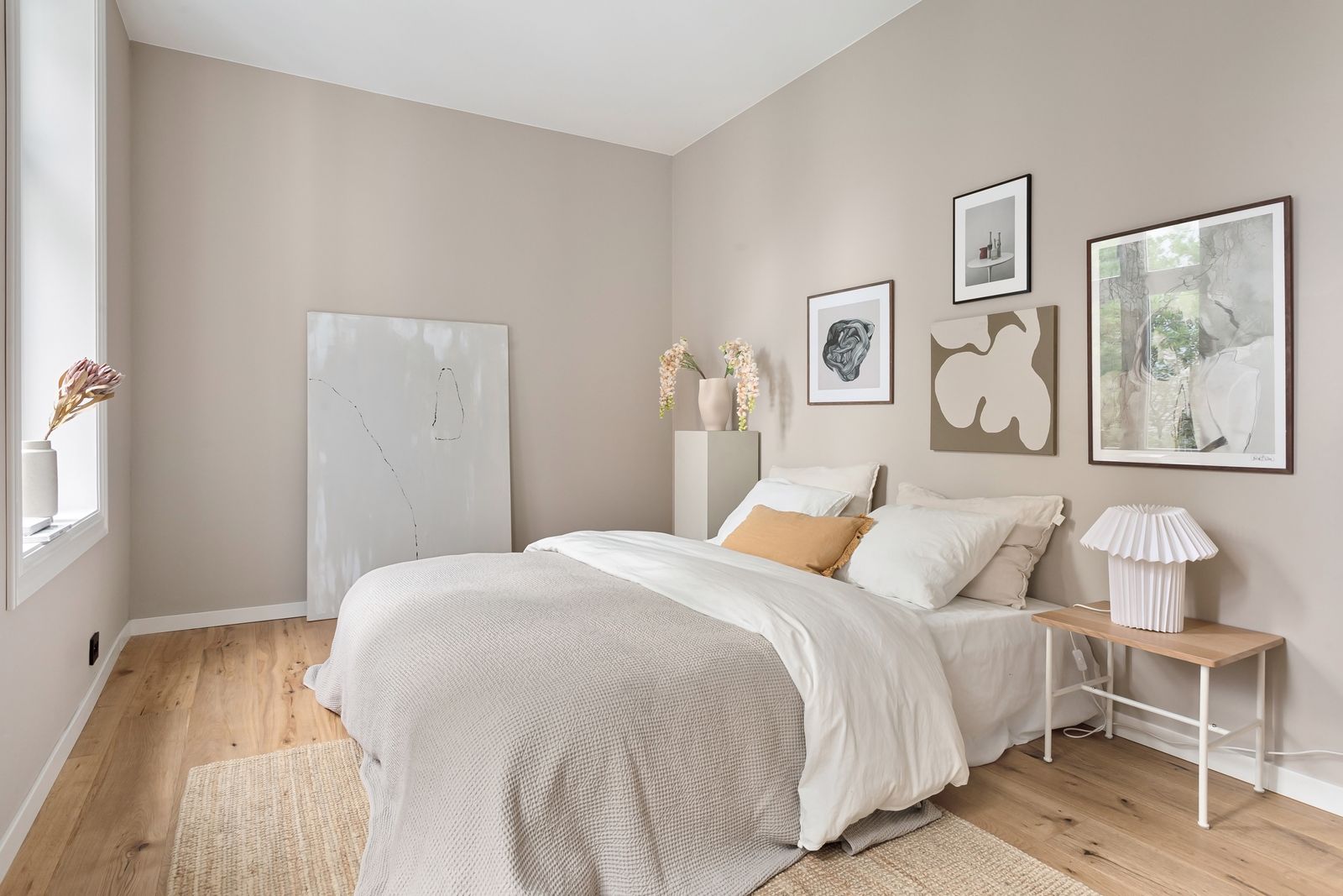 A serene minimalist bedroom with neutral tones, modern art, and soft bedding.