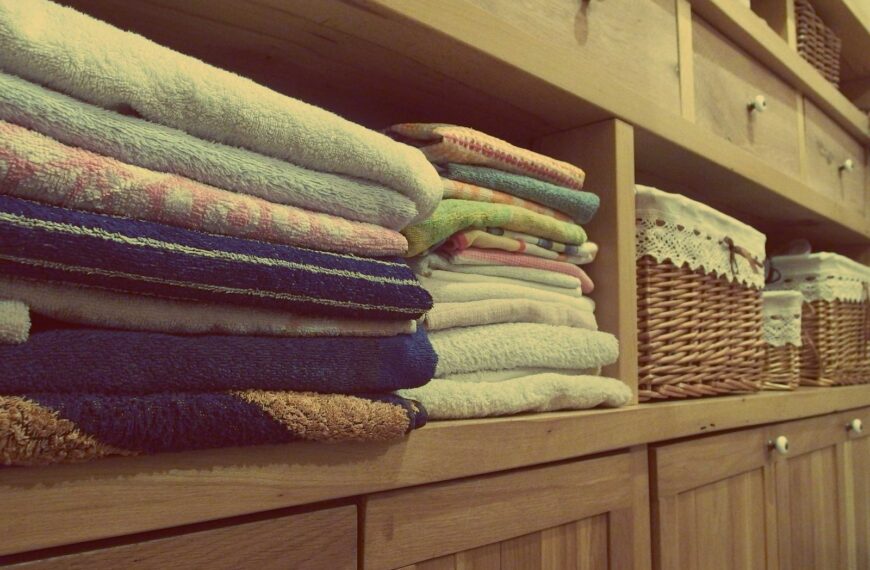 Tidy wooden cabinet with neatly stacked towels and decorative baskets in an indoor setting.
