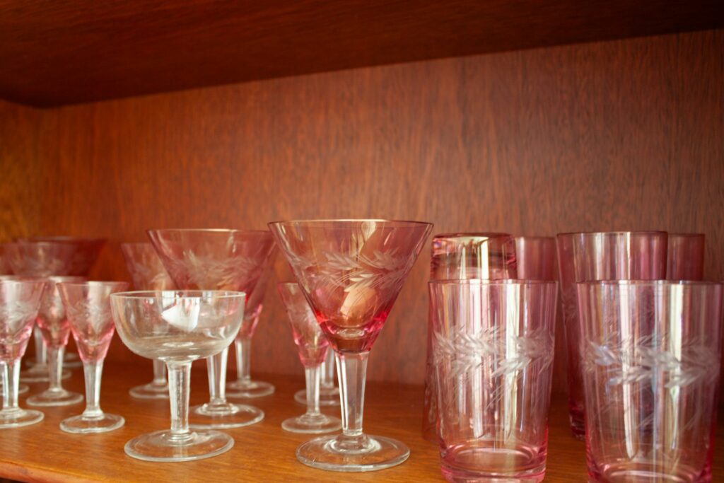 Pink and clear glassware displayed on a wooden shelf