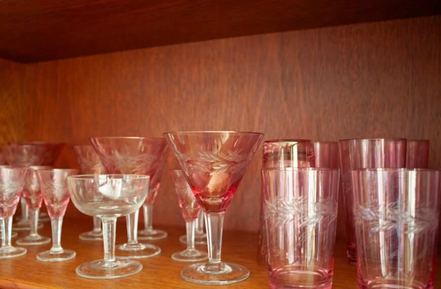 Pink and clear glassware displayed on a wooden shelf