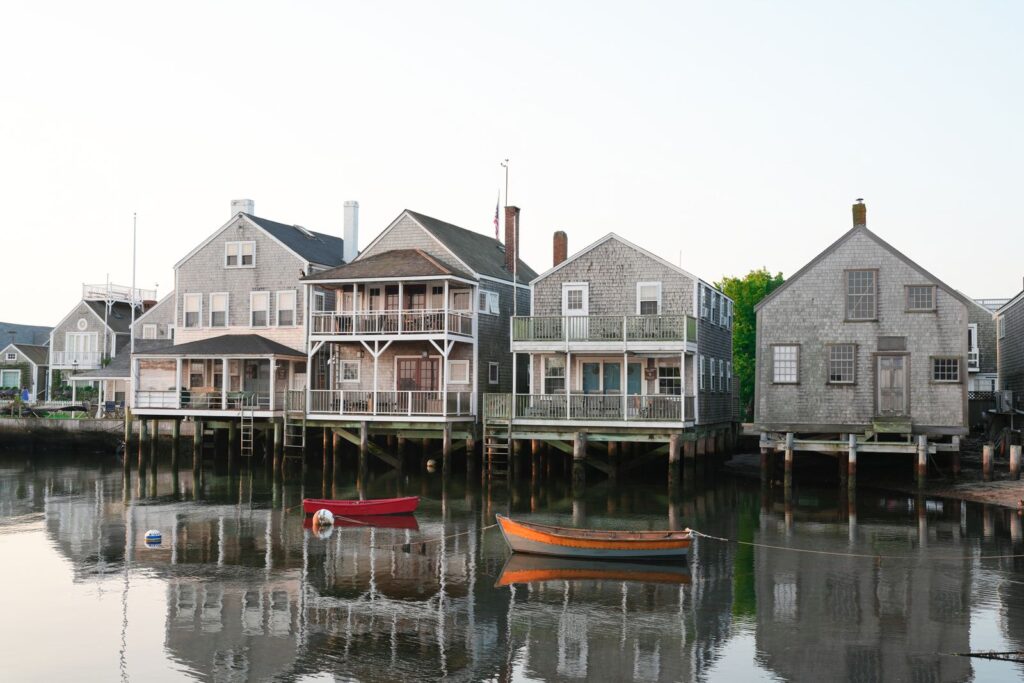 Quaint waterfront homes reflected in calm water at sunrise in Nantucket, Massachusetts.