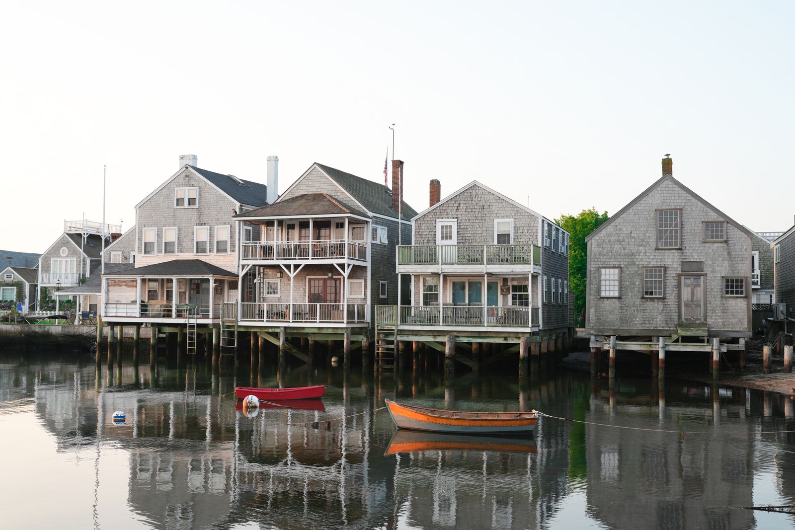 Quaint waterfront homes reflected in calm water at sunrise in Nantucket, Massachusetts.