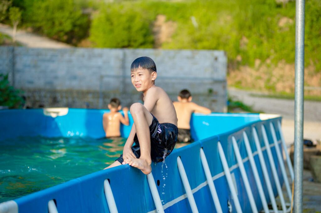 Kids playing and swimming in an outdoor pool in Hanoi, Vietnam, capturing joyful summer moments.