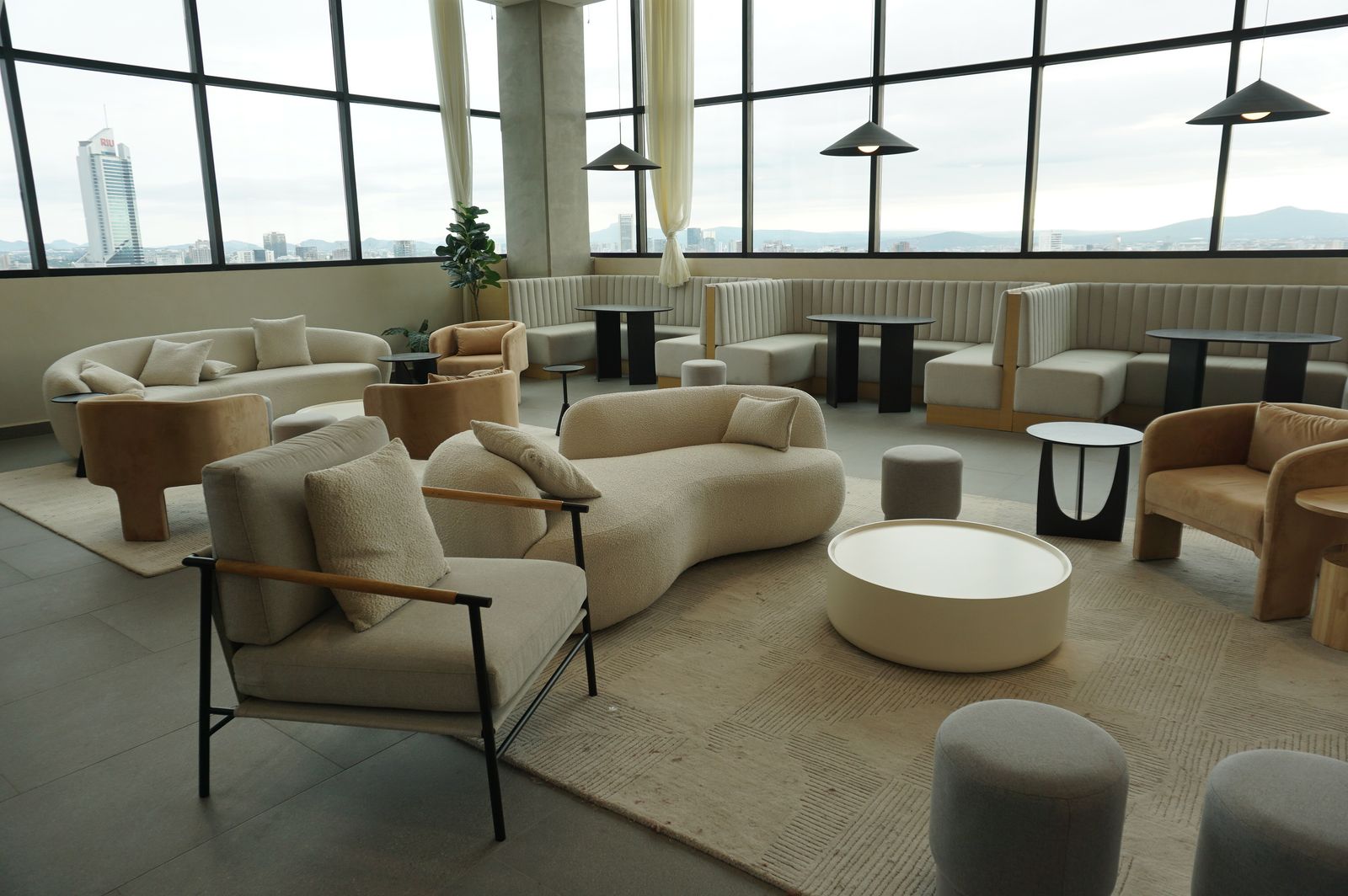 Spacious lounge featuring modern contemporary furniture with panoramic city view, ideal for meetings or relaxation.