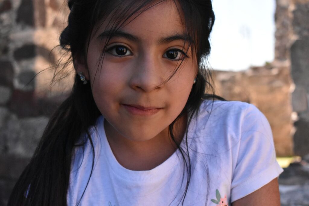 Close-up portrait of a young girl with natural light and soft focus outdoors, highlighting her serene expression.