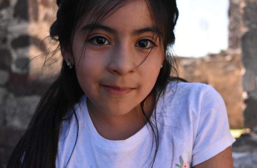 Close-up portrait of a young girl with natural light and soft focus outdoors, highlighting her serene expression.