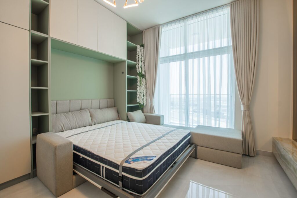 Stylish bedroom featuring a pull-down Murphy bed, elegant curtains, and bright lighting.