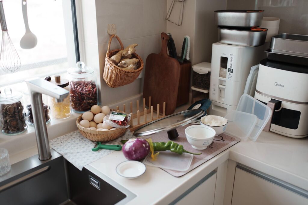 A kitchen counter with fresh ingredients ready for cooking, featuring eggs, vegetables, and kitchen gadgets.