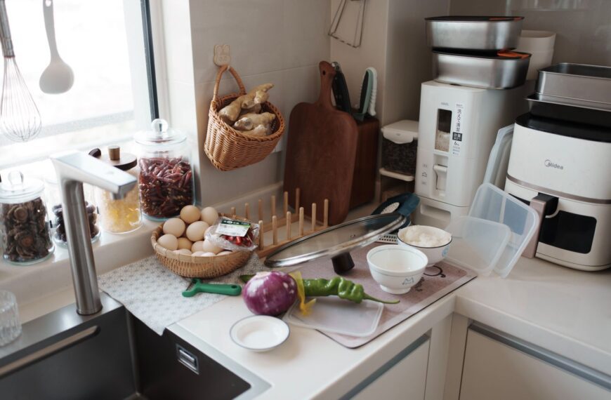 A kitchen counter with fresh ingredients ready for cooking, featuring eggs, vegetables, and kitchen gadgets.