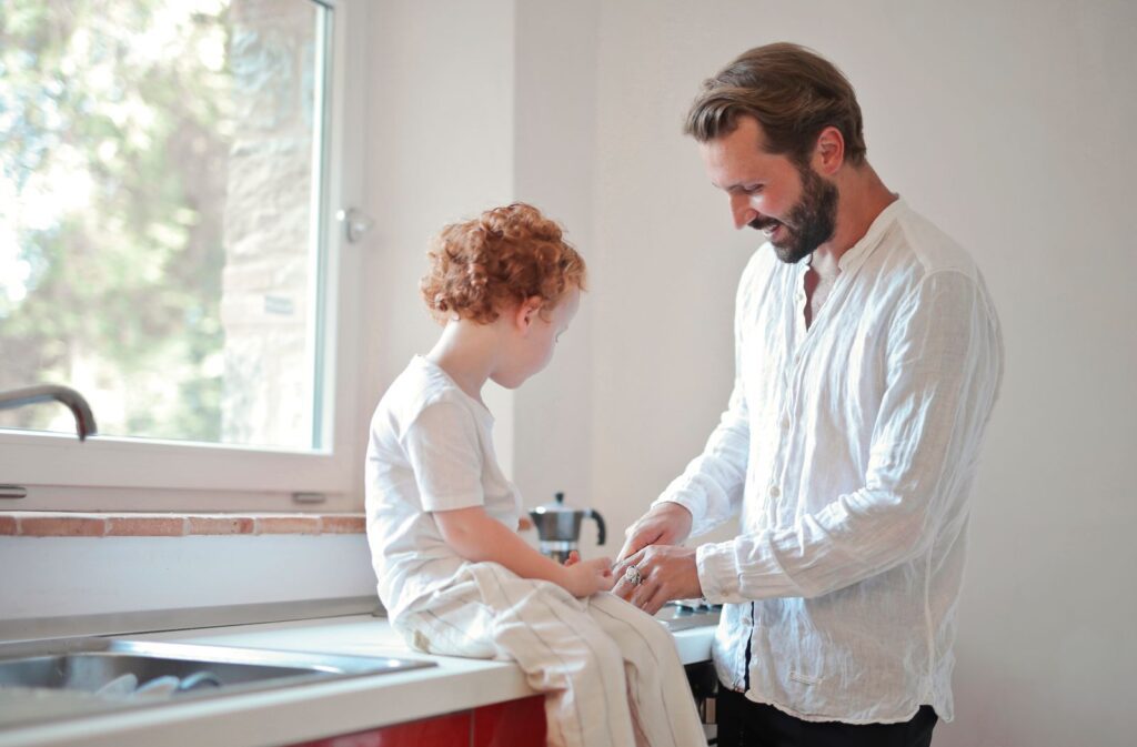 A loving father and son sharing a moment sitting by the kitchen sink.