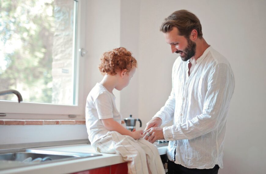 A loving father and son sharing a moment sitting by the kitchen sink.