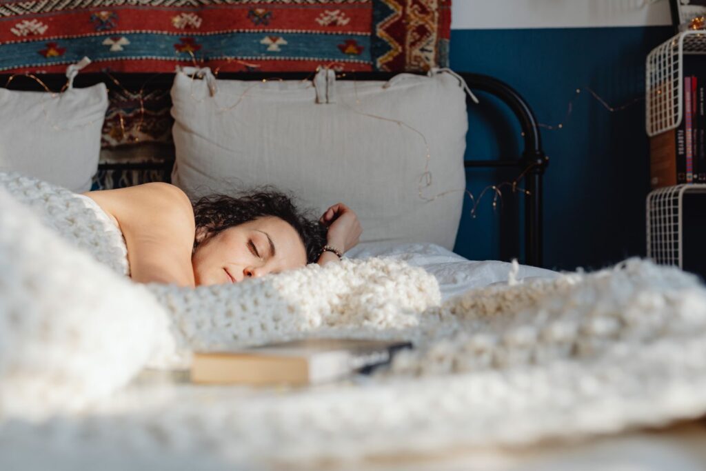 A woman peacefully sleeping on her side in a cozy, sunlit bedroom with decorative elements.