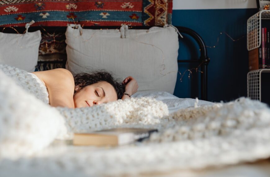 A woman peacefully sleeping on her side in a cozy, sunlit bedroom with decorative elements.
