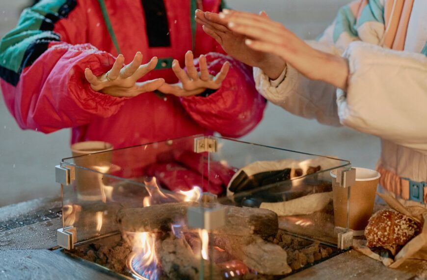 Hands warming over a campfire during a frosty winter evening, emphasizing companionship.