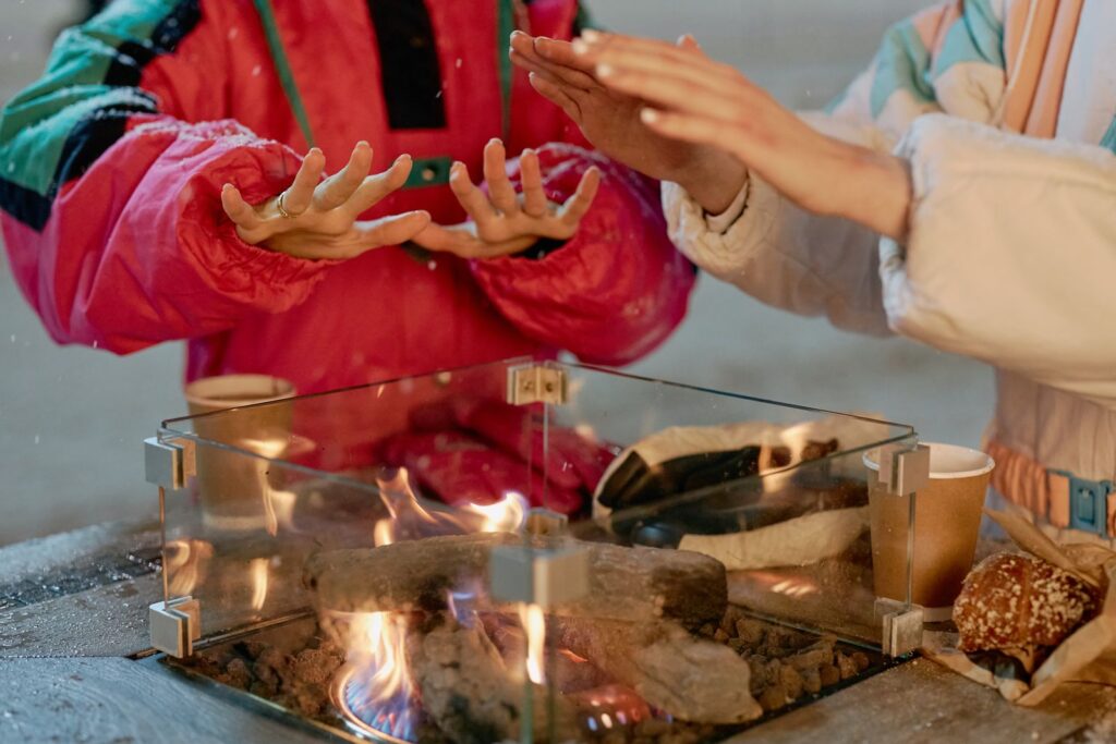 Hands warming over a campfire during a frosty winter evening, emphasizing companionship.