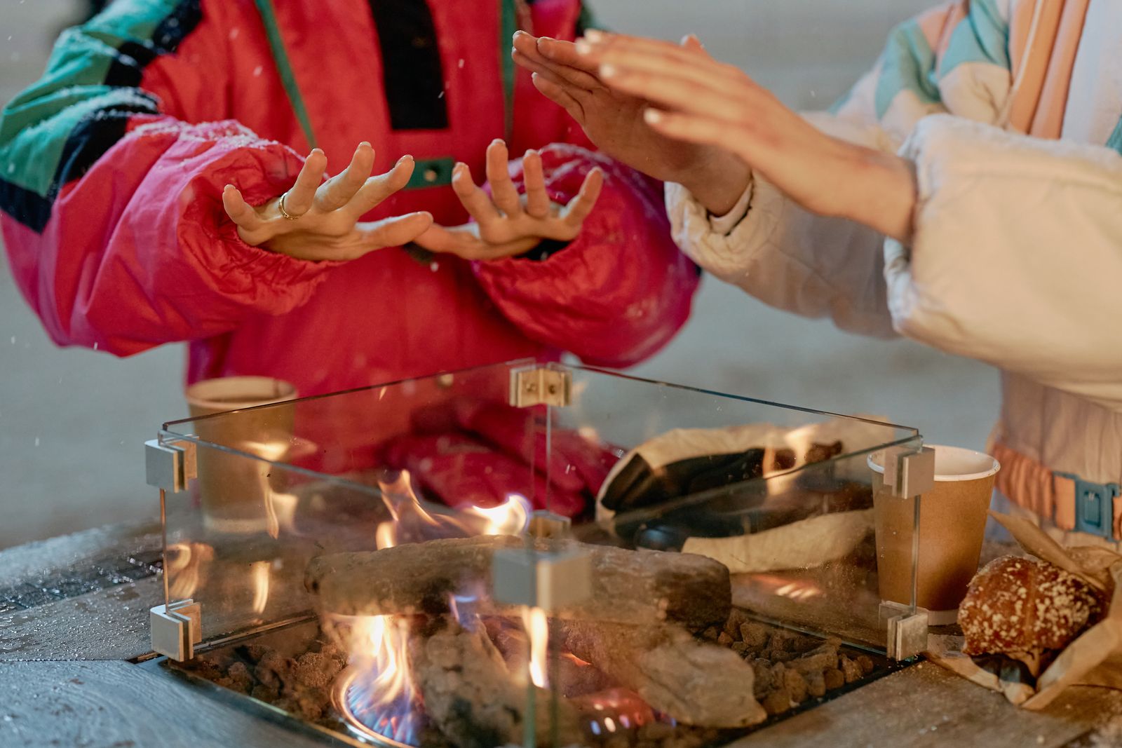 Hands warming over a campfire during a frosty winter evening, emphasizing companionship.