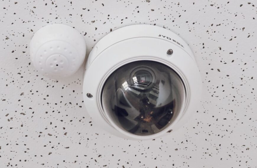 Close-up of a round dome surveillance camera installed on a speckled ceiling for security monitoring.