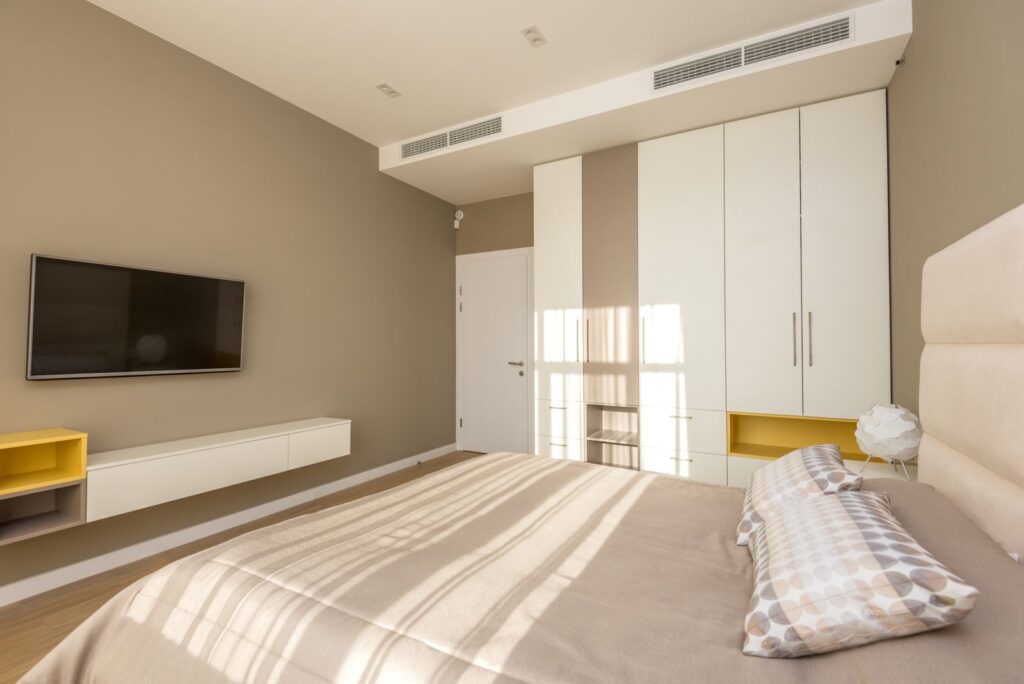 Bright and spacious modern bedroom with neutral tones and elegant decor.