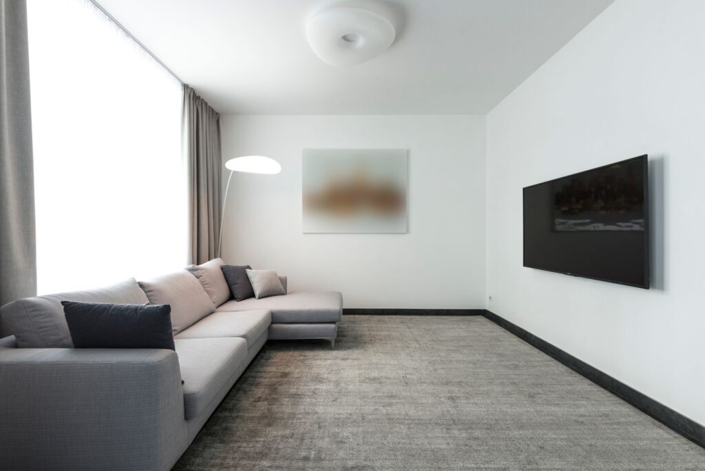 Contemporary living room with a gray sectional sofa and a wall-mounted TV.