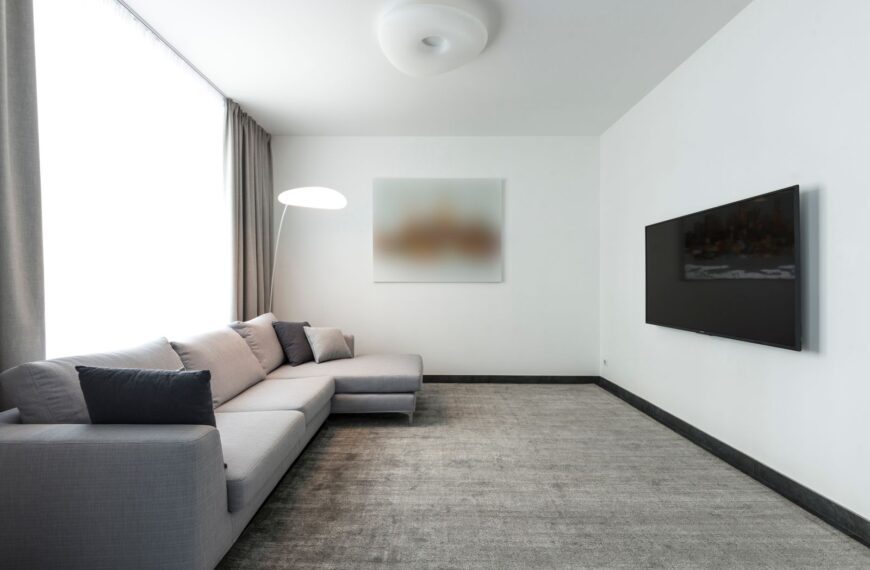 Contemporary living room with a gray sectional sofa and a wall-mounted TV.