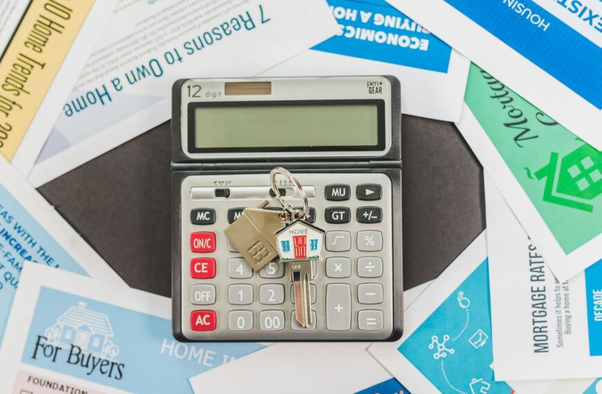 Calculator with keys and real estate documents symbolizes home buying finances.