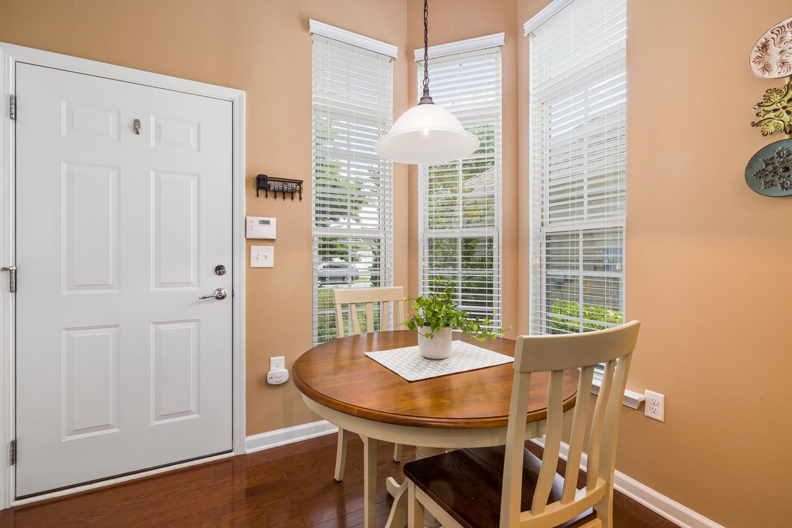 Bright dining area with round table, chairs, and houseplant by the window.