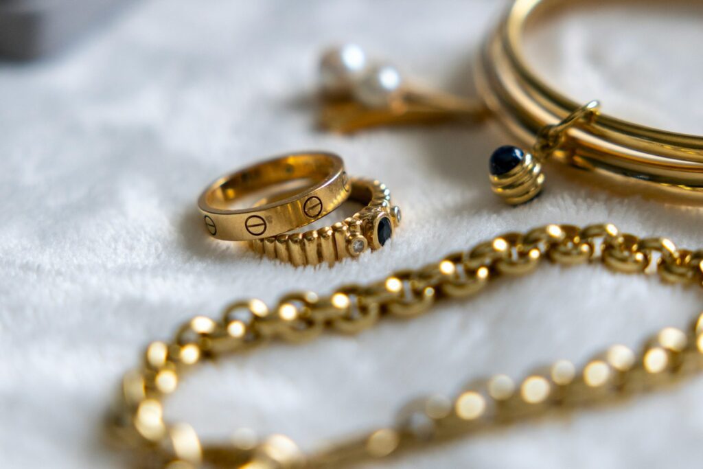 Golden jewelry is arranged on a soft white surface
