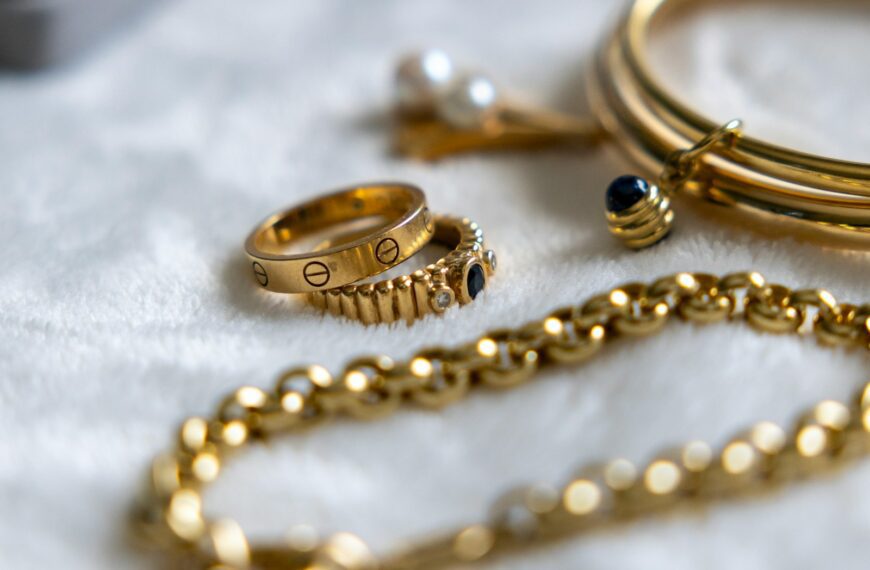 Golden jewelry is arranged on a soft white surface