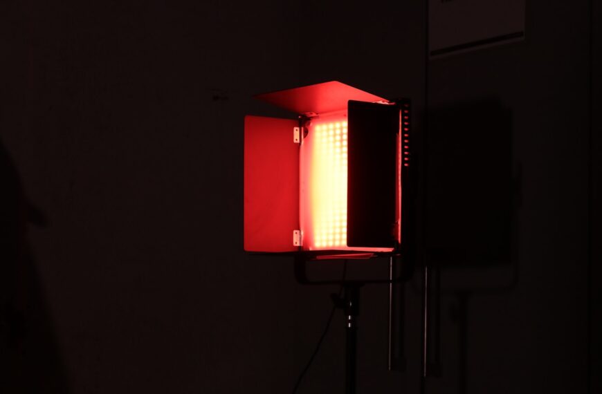 A red studio light illuminates a dark room