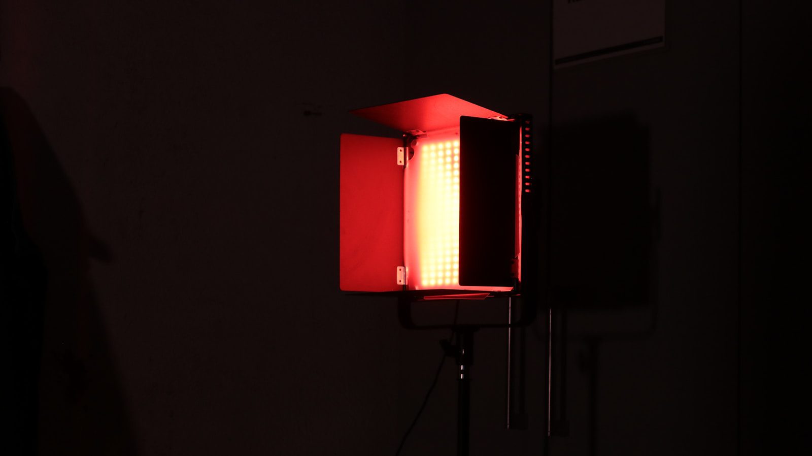 A red studio light illuminates a dark room