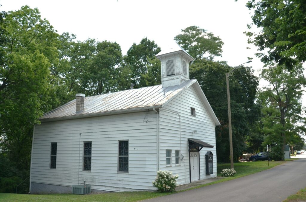 White building with a bell tower surrounded by green trees