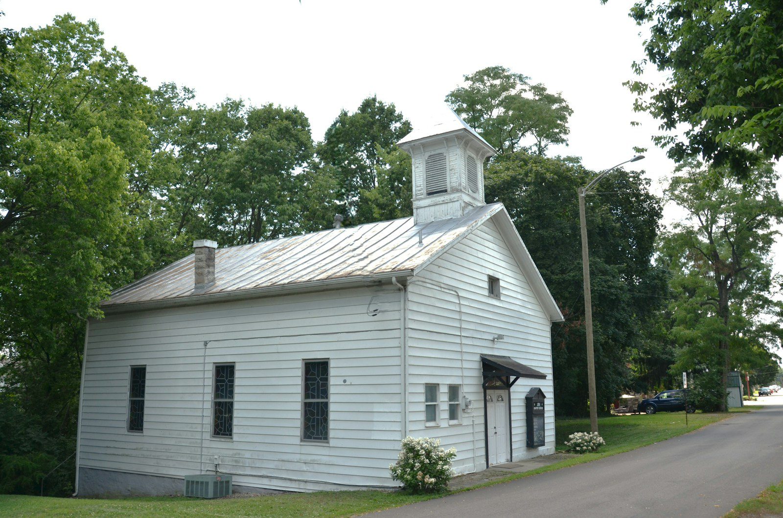 White building with a bell tower surrounded by green trees