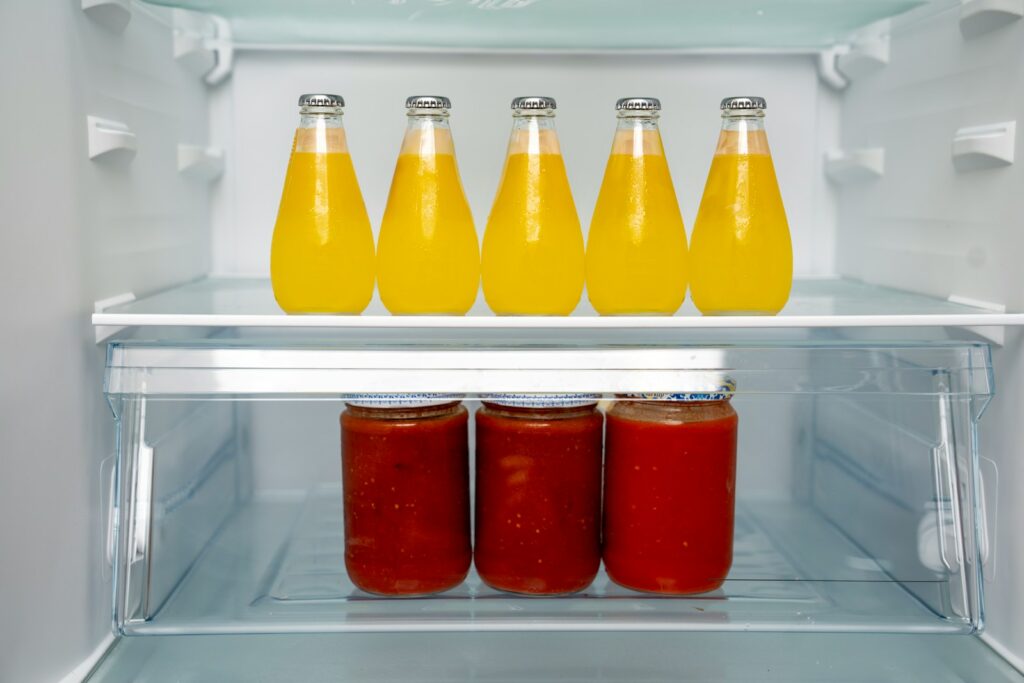 A refrigerator filled with lots of bottles of juice