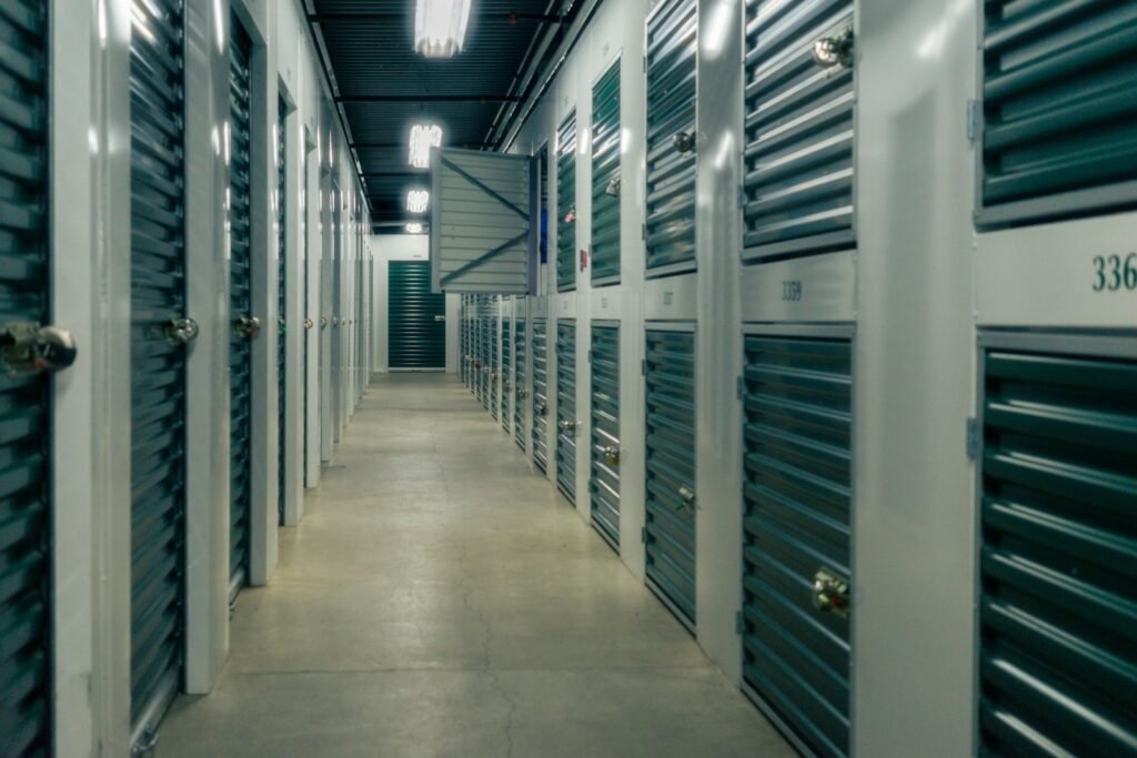 A long hallway lined with green metal storage unit doors and padlocks