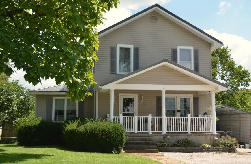 A two-story house with beige siding and a white front porch