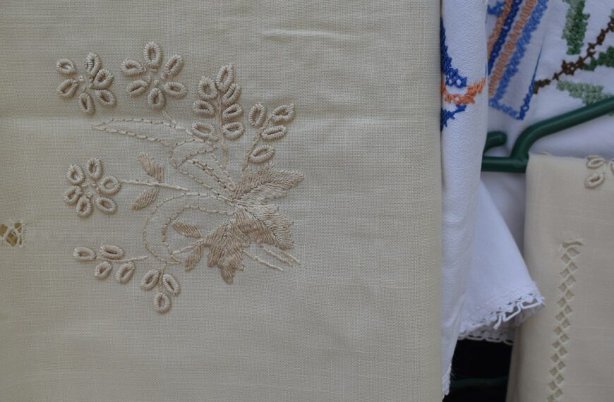 Beige fabric with delicate floral embroidery hanging beside white lace textiles