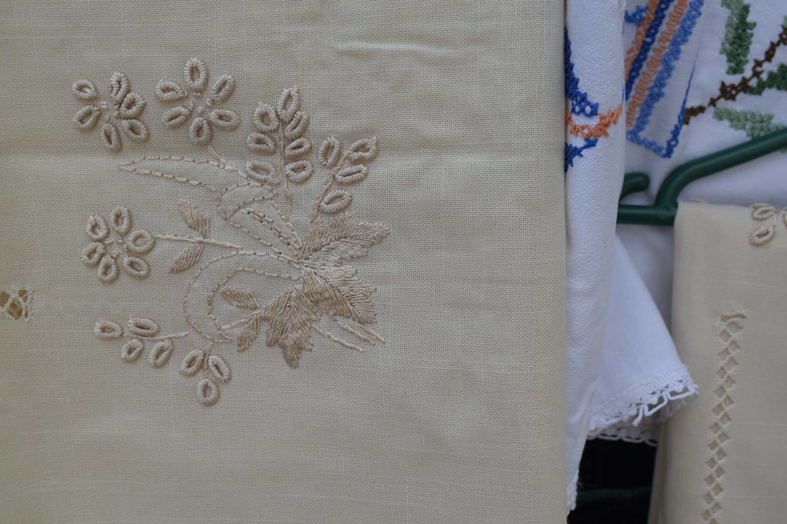 Beige fabric with delicate floral embroidery hanging beside white lace textiles