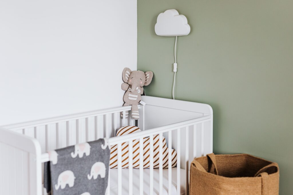An empty white crib in a softly decorated nursery