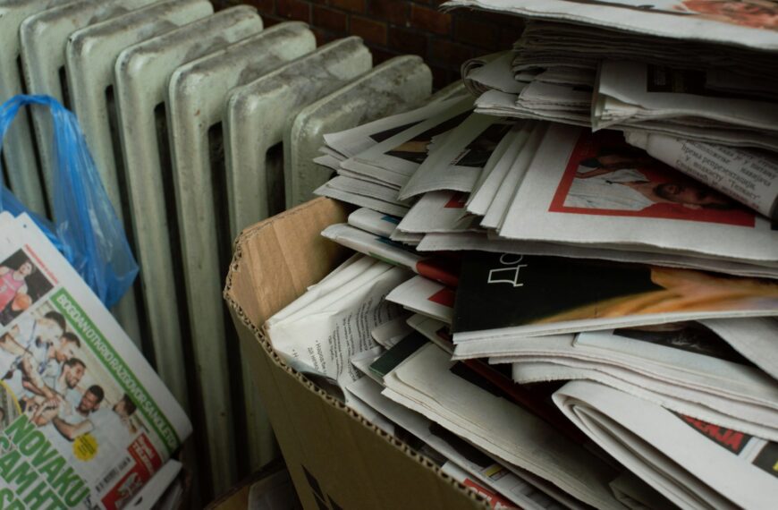 a cardboard box full of newspapers next to a radiator