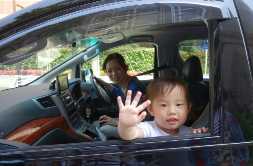 Child waves from car window with mother driving