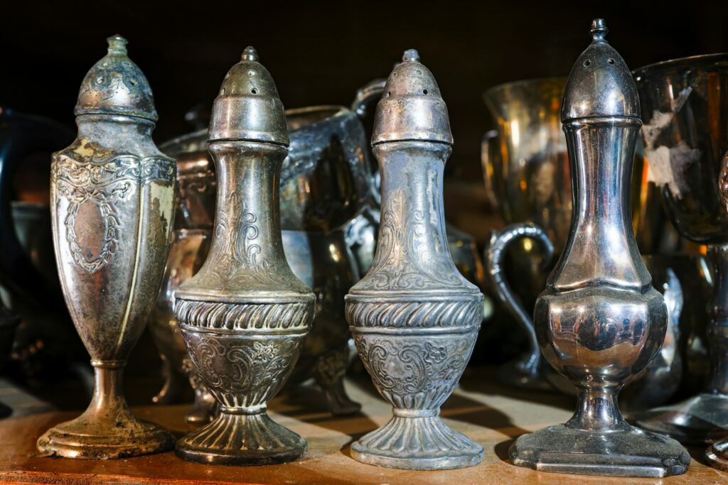 a group of silver vases sitting on top of a wooden table