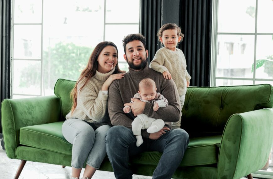a family sitting on a green couch in a living room