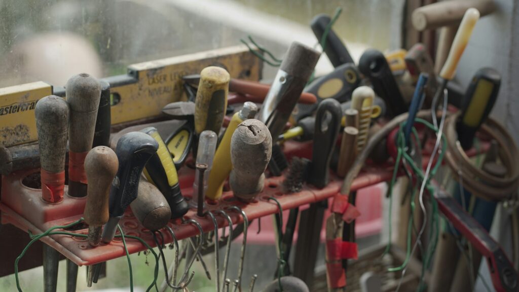 Assorted hand tools with wooden and plastic handles stored in a red rack