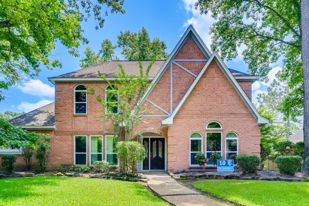 Two-story brick suburban house with landscaped front yard in daylight