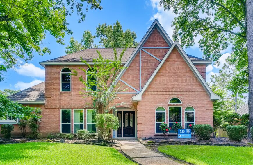 Two-story brick suburban house with landscaped front yard in daylight