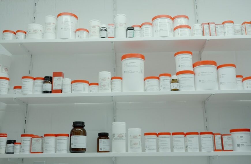 a shelf filled with lots of white and orange medicine bottles