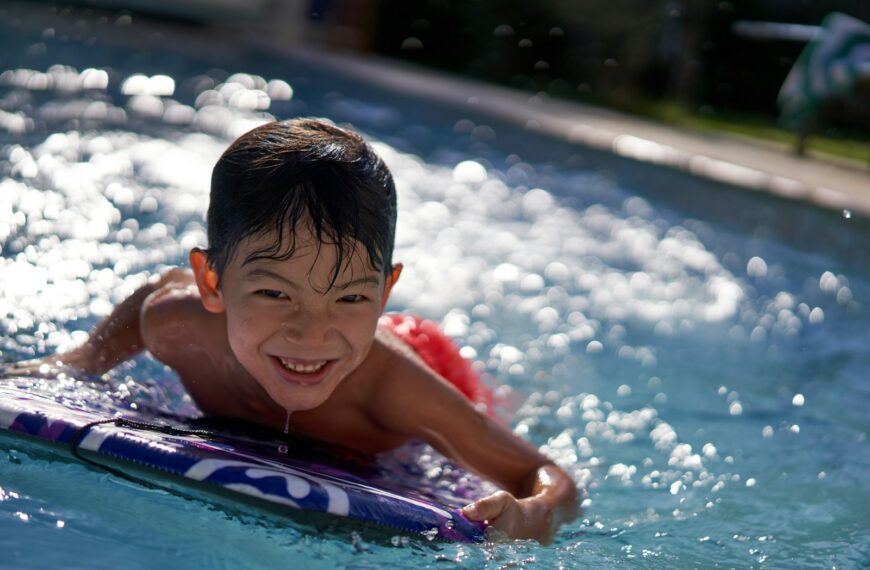 boy in pool smiling during daytime