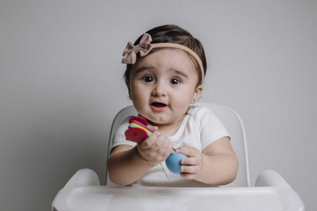 a baby sitting in a high chair holding a toy